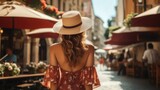 Fototapeta Uliczki - Woman in a sun hat walking on European city street, Travel concept, Backside view.