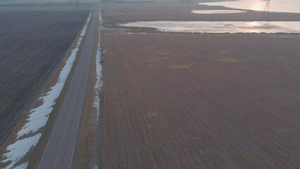 Poster - Drone view of a narrow road in rural field at sunset