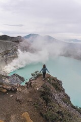 Wall Mural - Aerial view of a hiker on a cliff over an acid lake with sulfur steam at Mount Ijen, Java,Indonesia