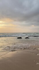 Poster - Vertical aerial view of beautiful waves crashing against a Bali seashore at sunset