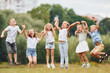 © standret - Holding each other by hands and jumping. Kids are having fun on the field at daytime together