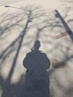 La silueta en sombra de un hombre entre las sombras de los árboles en la superficie del camino de asfalto gris,  produce un diseño abstracto natural para fondos