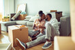 © Marko Geber - Young African American couple taking a break from moving in to have wine and snacks in their new apartments living room