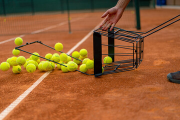 close-up of many tennis balls falling out of basket on clay tennis court sport competition training