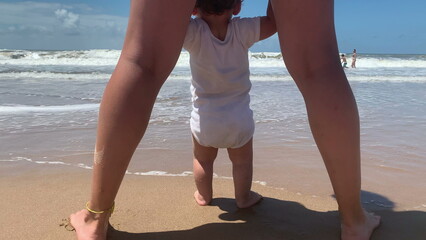 Wall Mural - Baby and mother at beach taking first steps at sea shore vacations