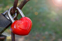 Close Up Of Red Heart-shaped Love Lock Hanging On A Bridge. Valentine's Day And Love Concept.