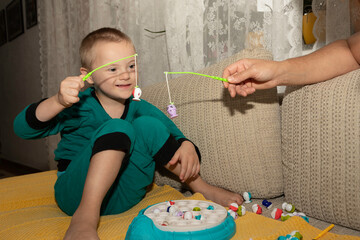 Wall Mural - Parent and child playing with toys. A young boy with Down Syndrome plays with his mother. 