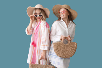 Sticker - Young sisters in summer hats and sunglasses on blue background