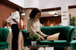 © DC Studio - Female manager checking bureaucracy to review booking forms, sitting on couch in lounge area. Young hotel concierge working on registration details, providing luxury resort service.