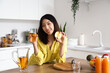 © Pixel-Shot - Beautiful Asian woman with glass of juice and apple in kitchen