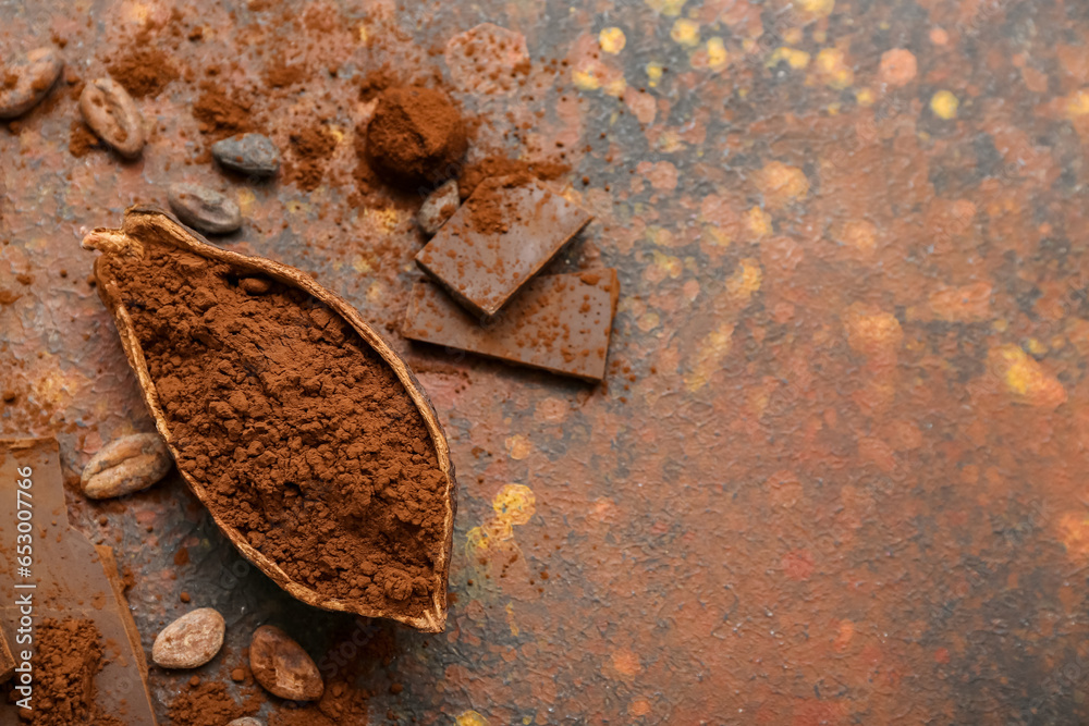 Cocoa pod with powder, beans, candy and chocolate on grunge background
