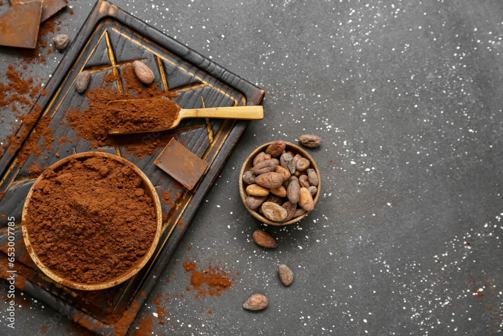 Bowls with cocoa powder, chocolate and beans on black background