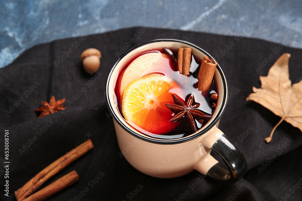 Cup of hot mulled wine with orange and apple on blue background