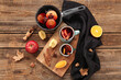 Cups and saucepan of hot mulled wine with apple on wooden background