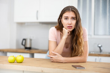 Wall Mural - Portrait of a frustrated young woman standing in a home kitchen