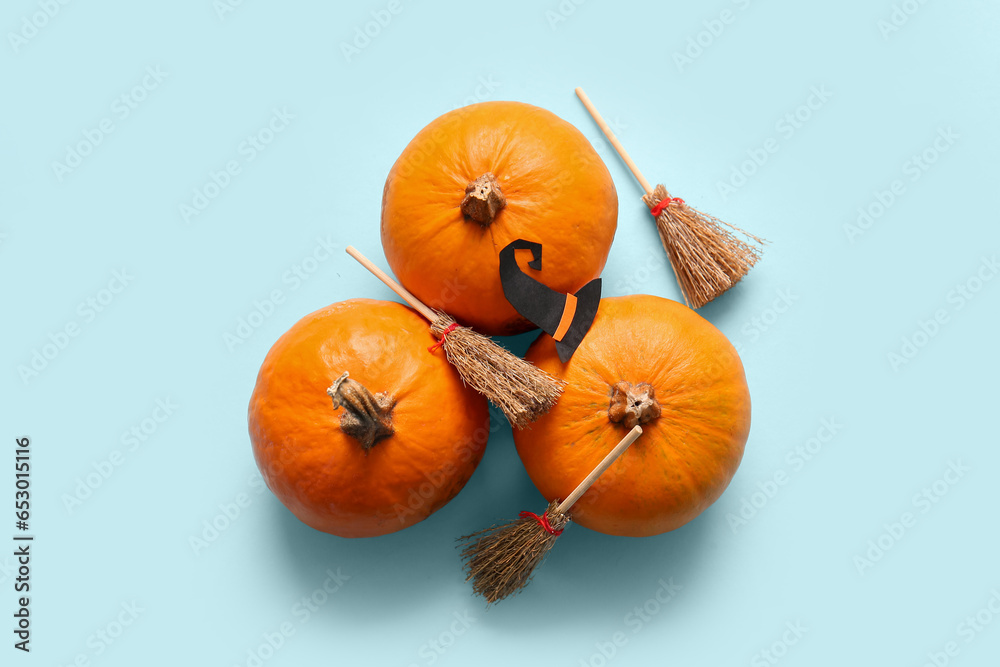 Halloween composition with pumpkins, brooms and witch hat on blue background
