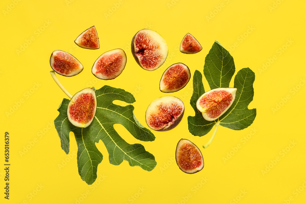 Cut fresh figs and leaves on yellow background