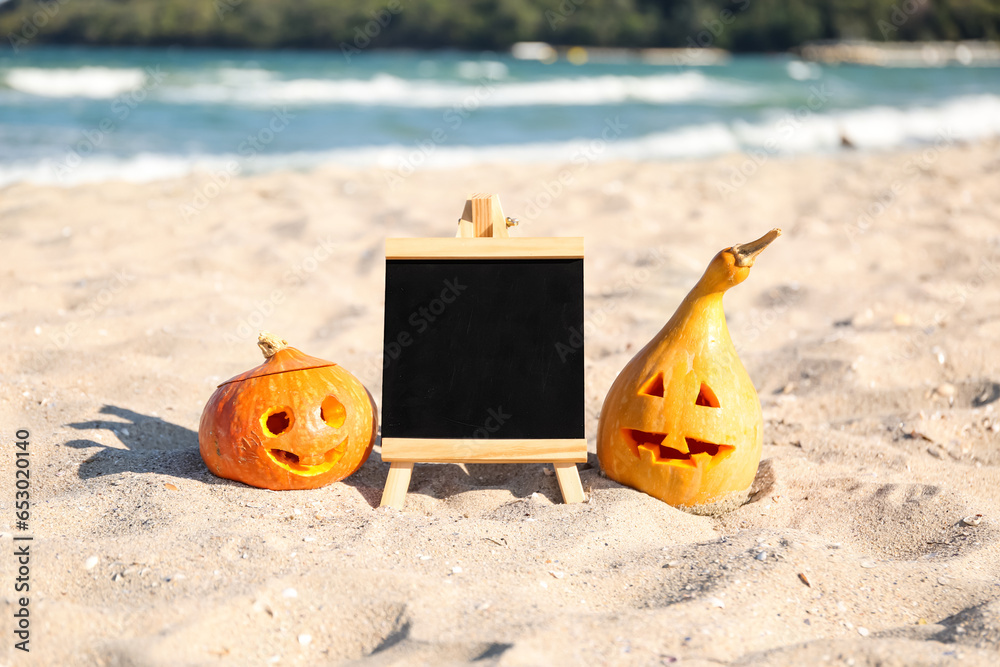 Carved pumpkins for Halloween with blackboard on beach
