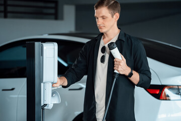 Young man travel with EV electric car to shopping center parking lot charging in downtown city showing urban sustainability lifestyle by green clean rechargeable energy of electric vehicle innards