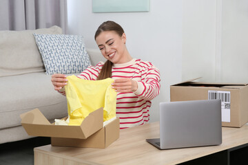 Poster - Happy woman unpacking parcels at home. Online store