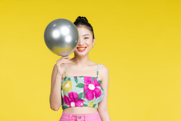 Wall Mural - Smiling beautiful young asian woman dancing with silver balloons.