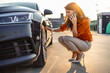 © Graphicroyalty - Woman calling for assistance with flat tire on car in the city. Young woman with high heels in the city with flat tire, frustrated near broken car