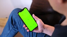 Unrecognizable Man Sitting On The Couch In A Living Room, Using His Smartphone And Swiping Left And Right In Dating App. App Template, Green Screen With Tracking Markers. Browsing On The Internet. 4K