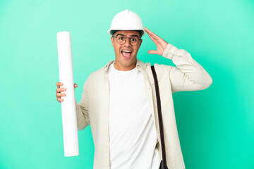 Wall Mural - Young architect man holding blueprints over isolated background with surprise expression