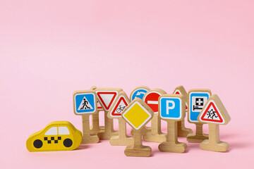 Poster - Set of wooden road signs and car on light pink background. Children's toy