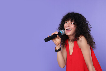 Sticker - Beautiful young woman with microphone singing on purple background. Space for text