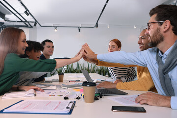 Poster - Team of employees joining hands at white table in office. Startup project