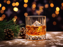 A Glass Of Whiskey Or Rum On A Wooden Table With A Fir Branch And Pine Cones With Blurry Lights Background. Empty Space For Product Placement Or Advertising Text.
