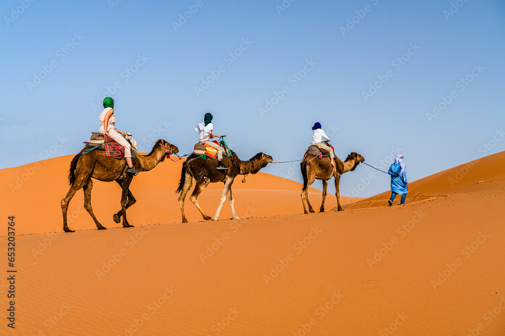 Family with one child enjoying a camel ride in the desert, Erg Chebbi ...