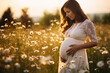 beautiful pregnant woman enjoying the summer sun on a flowers meadow