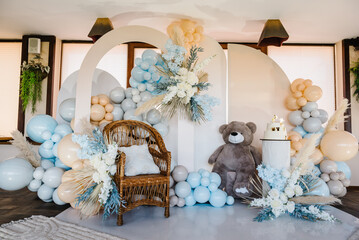 Wall Mural - Photo wall decoration blue, brown, grey balloons, autumn decor with dry leaves, flowers. Arch with bear, wicker wooden chair. Trendy cake for celebration baptism. Delicious reception at birthday party