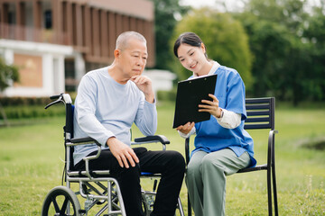 Elderly asian senior man on wheelchair with Asian careful caregiver. Nursing home hospital garden concept.