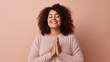 Studio image of a multicultural woman happily doing yoga against a light beige background.