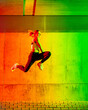 © VISTA by Westend61 - Active woman jumping in front of neon colored wall