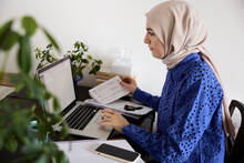 Businesswoman in headscarf working on laptop at home