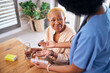 © Phindulo T/peopleimages.com - Nurse, smile and giving old woman pills in home with water for healthcare, wellness and support. Caregiver, medicine and African patient with glass to drink medical drugs, supplements and retirement