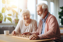 Beautiful Loving Couple In A Retirement Home. Senior Man And A Senior Lady Playing Table Game In A Nursing Home. Housing Facility Intended For The Elderly People.