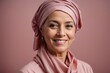 © kapros76 - Middle-aged woman cancer patient wearing headscarf and smiling on solid pink background. Generative Ai.