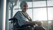 © tong2530 - Happy senior female cancer patient wearing head scarf in wheelchair at hospital. Generative Ai
