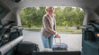 © Miljan Živković - mature blonde woman travel take stuff belongings from the back of car