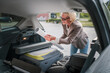 mature blonde woman travel take stuff belongings from the back of car