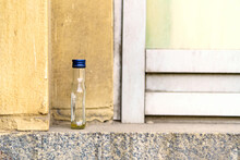 A Small Empty Bottle Of Alcohol Stands On The Windowsill