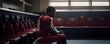 Upset football player in red uniform sitting alone on bench in sports changing room