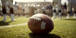 Blurred legs of football players standing around oval ball on sport field during american football match