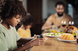 © Goran - Black boy using smart phone at dining table while his father and sister are in the background
