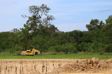 An Road Roller Car And A Pile Of Dirt In A Road Construction Area.